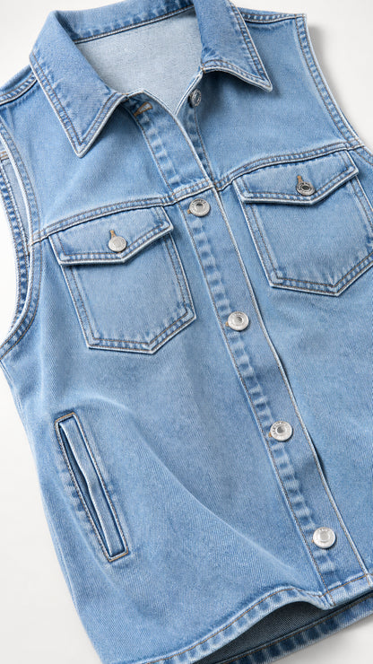 Close-up detail of light blue denim vest showing collar and button pockets