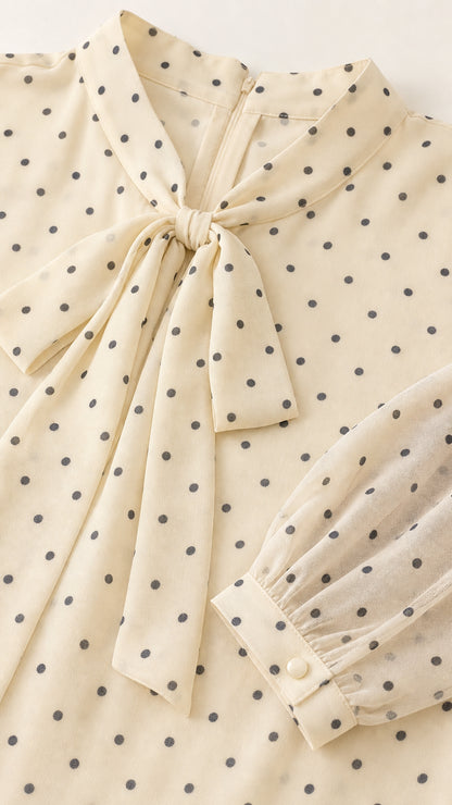 Close up of collar, bow, and sleeve details of cream polka dot dress
