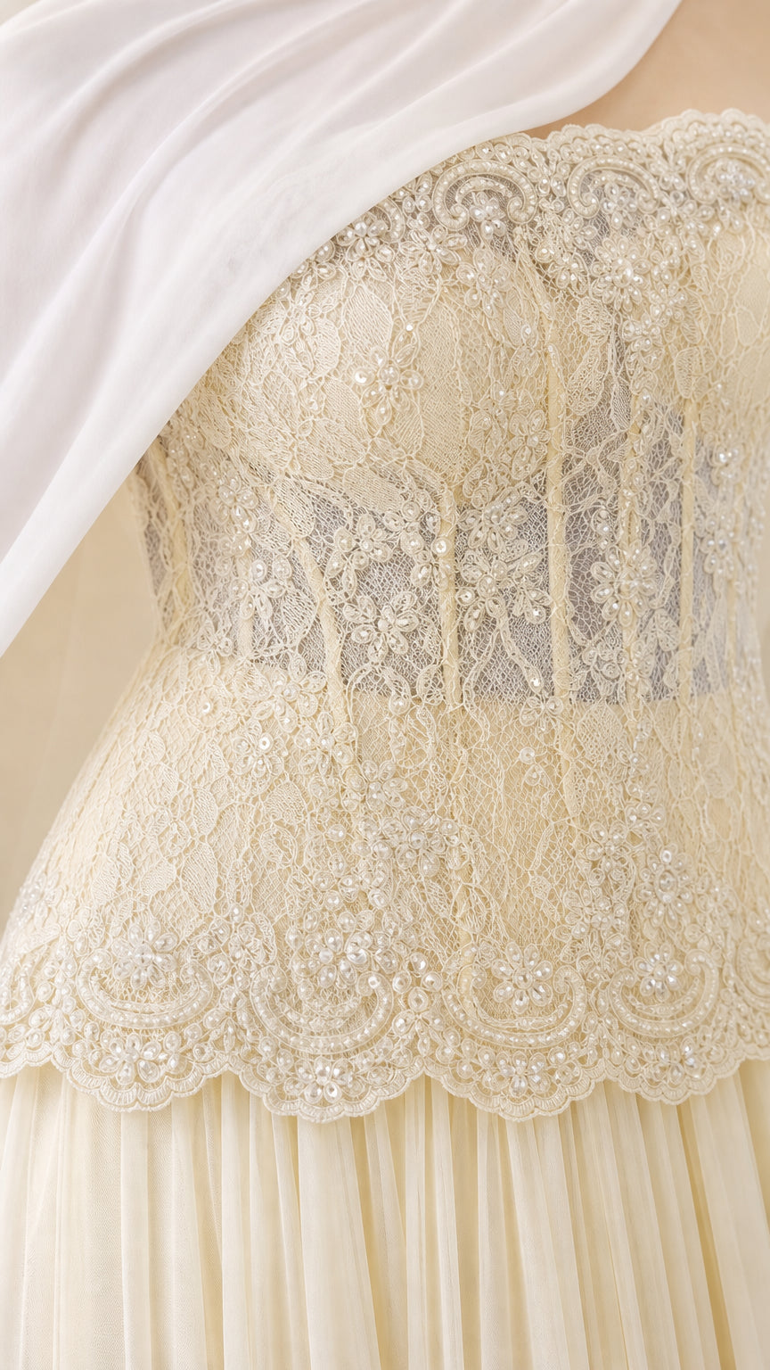 Close up detail of ivory lace corset bodice with delicate embroidery and scalloped peplum