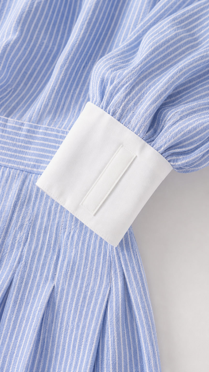 Close-up detail of light blue striped fabric and crisp white cuff sleeve