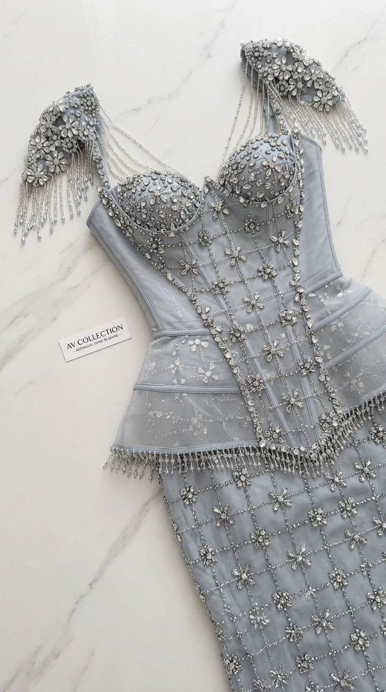 Close-up flat lay of dusty blue corset bodice with beadwork and fringe shoulder strap