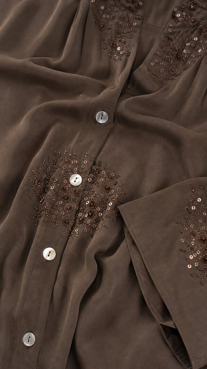 Close-up detail of embroidery and buttons on brown shirt