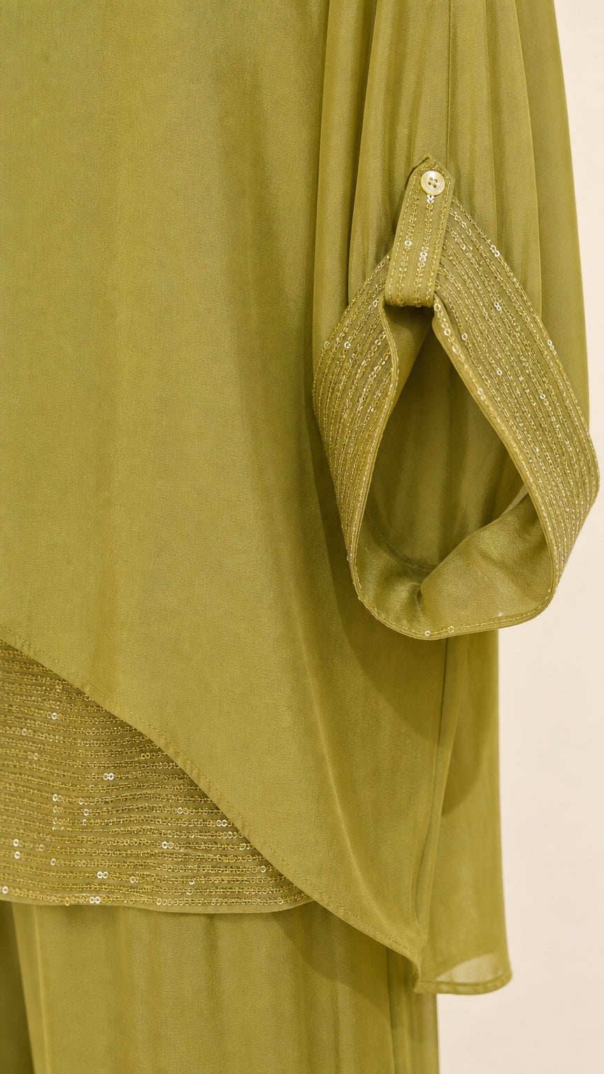 Close-up of sleeve cuff with button tab and sequin-trimmed layered hem