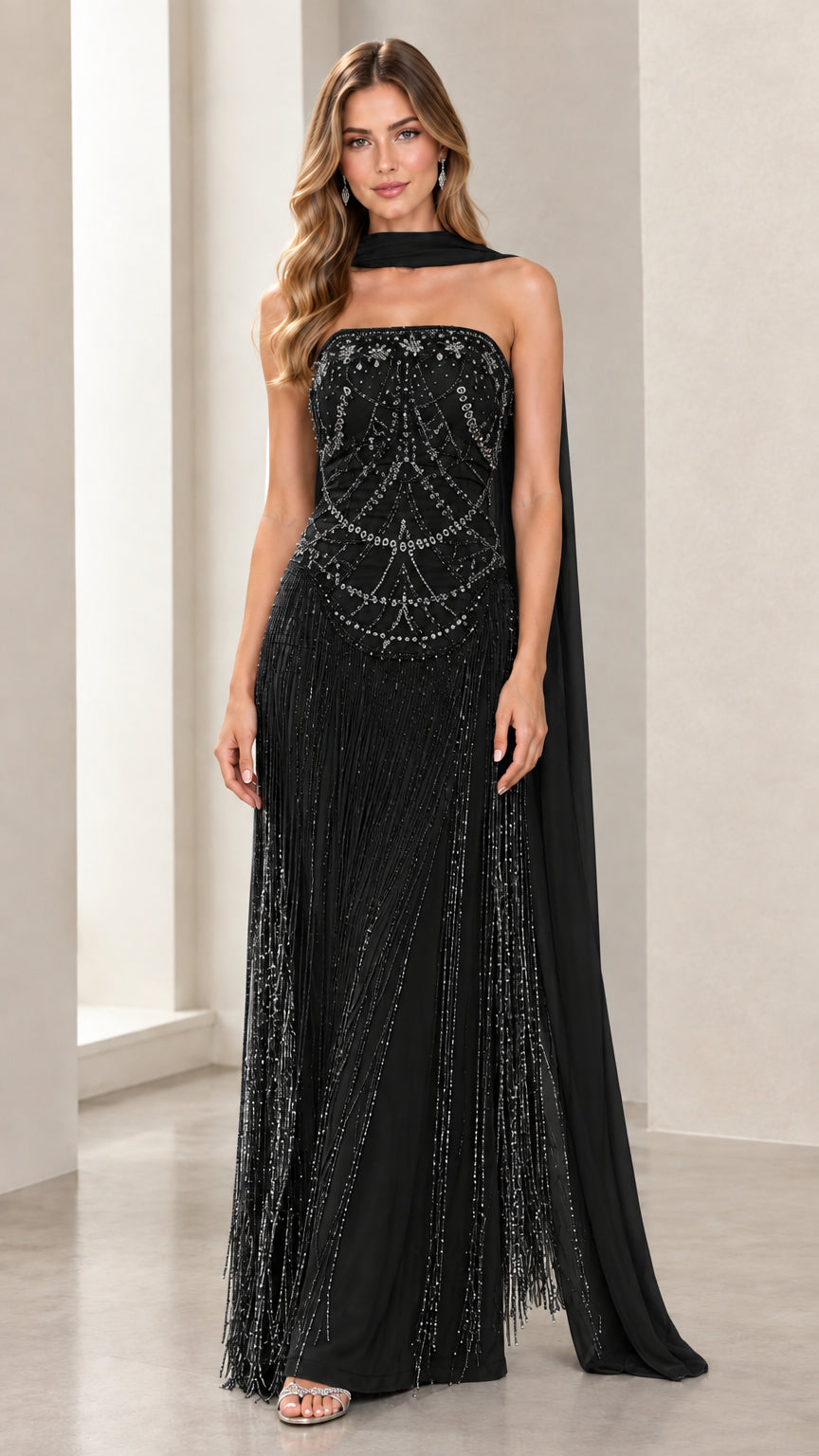Front view of model wearing Black strapless beaded fringe evening gown with black scarf cape
