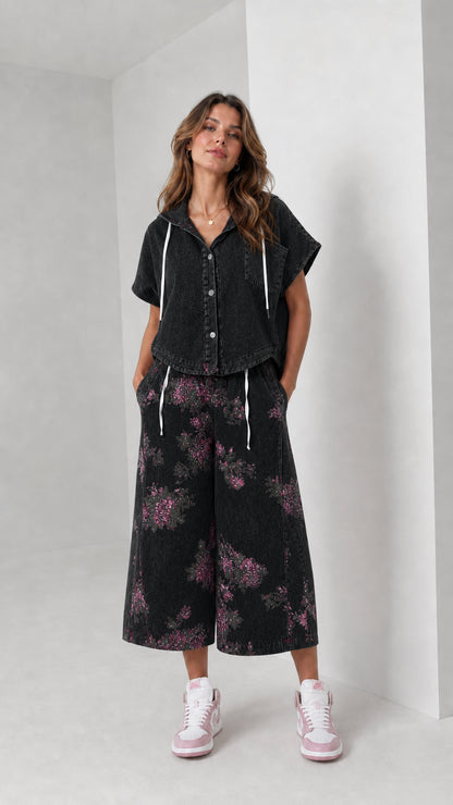 Front view of woman wearing washed black hooded shirt and floral wide-leg pants set