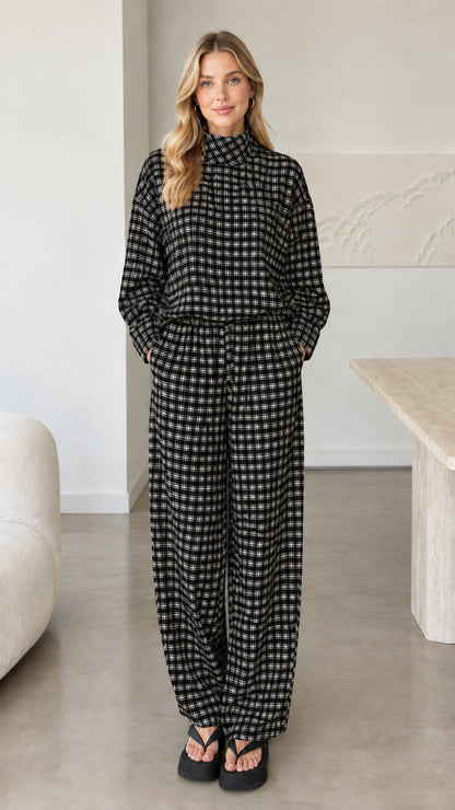 Front view of woman wearing black plaid mock neck top and wide leg pants set