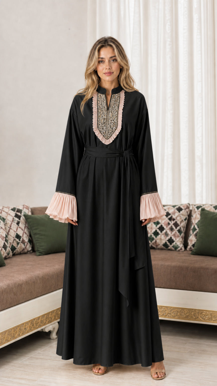 Front view of woman wearing black embroidered maxi abaya dress with blush pleated accents
