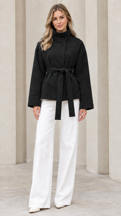 Front view of model wearing black stand collar belted jacket