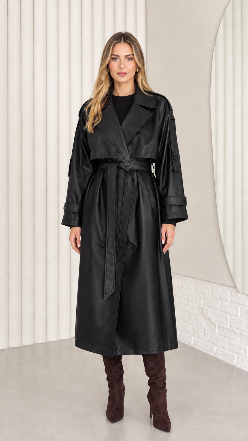 Full-length front view of woman wearing black faux leather belted trench coat