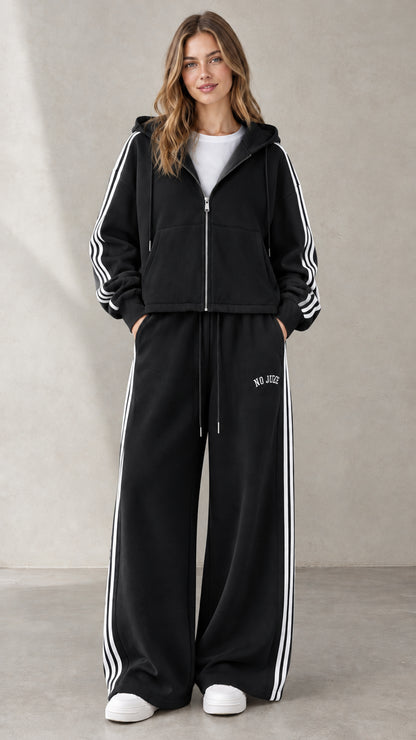 Woman wearing Black two-piece side-stripe zip-up hoodie and wide-leg sweatpants set
