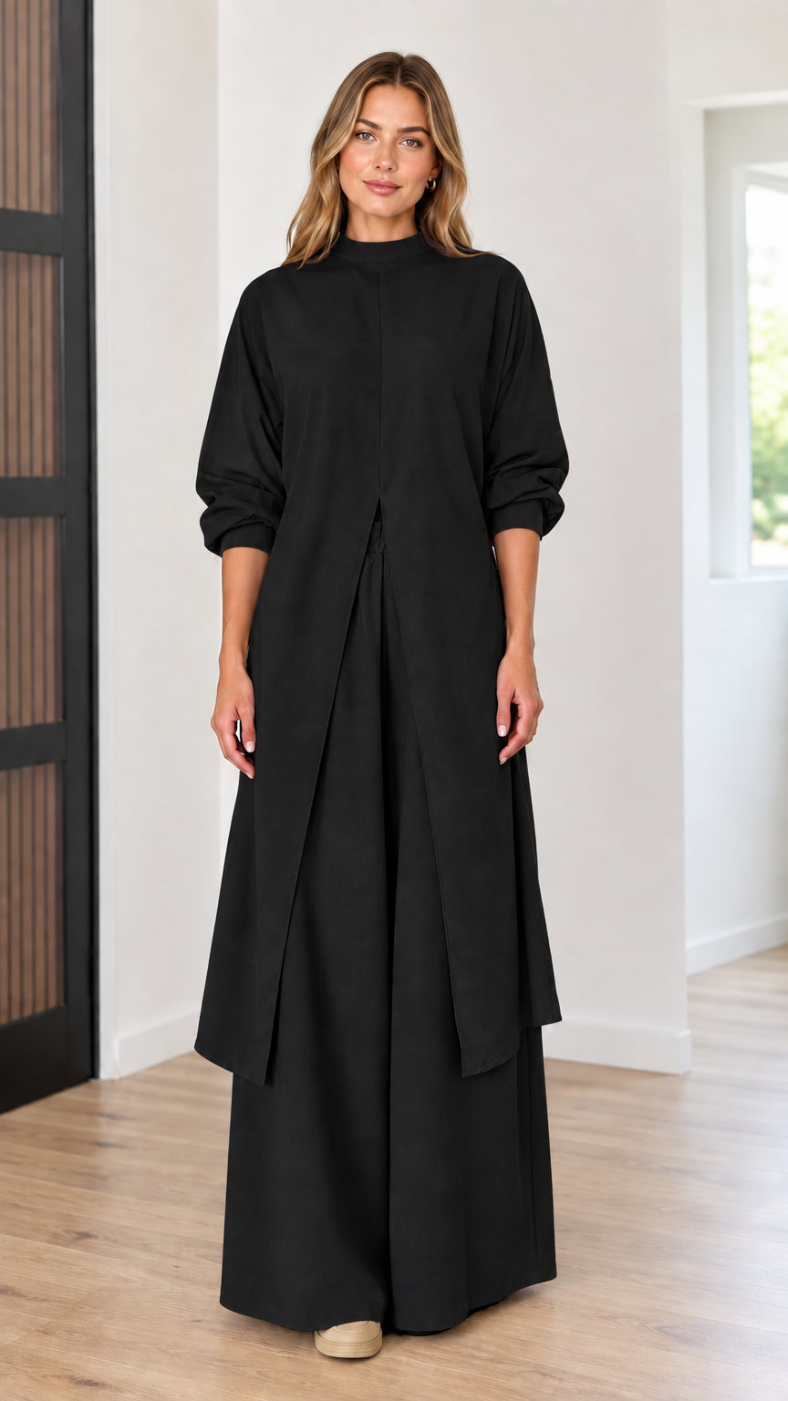 Full-length front view of model wearing black longline slit tunic top and wide-leg pants set