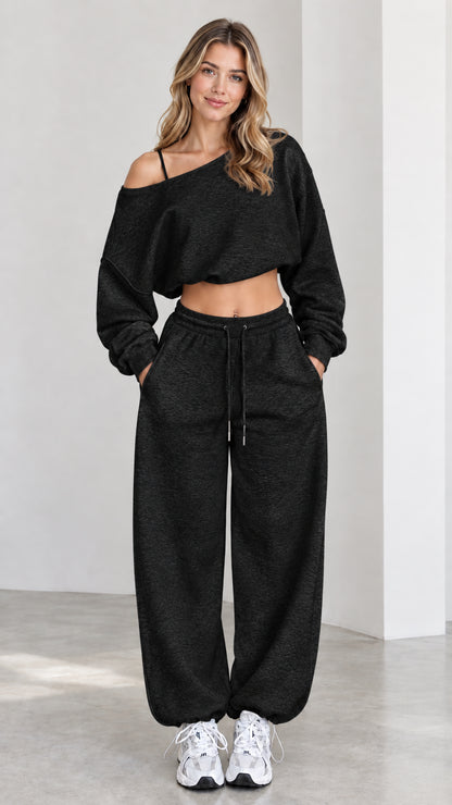 Model wearing black asymmetrical one-shoulder cropped sweatshirt and matching sweatpants set