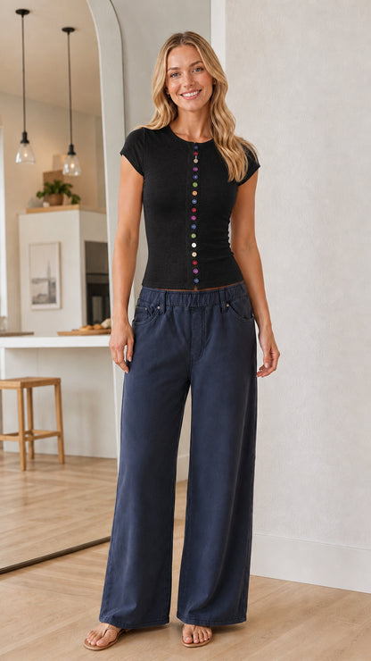 Full-body view of a model wearing a black short sleeve top with colorful buttons
