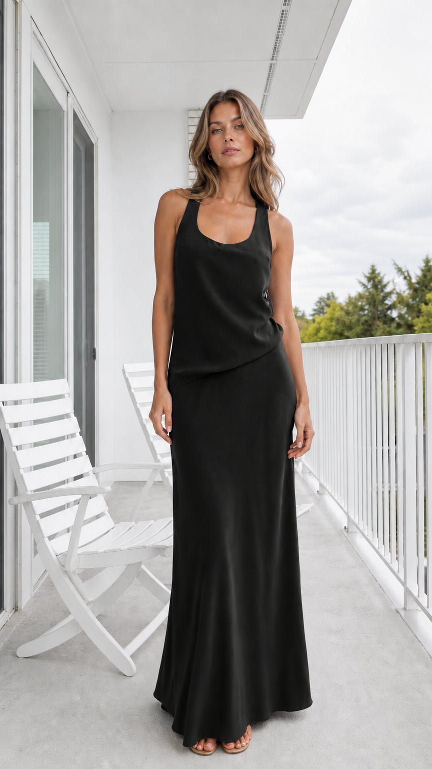 Model wearing classic black sleeveless draped overlay maxi dress