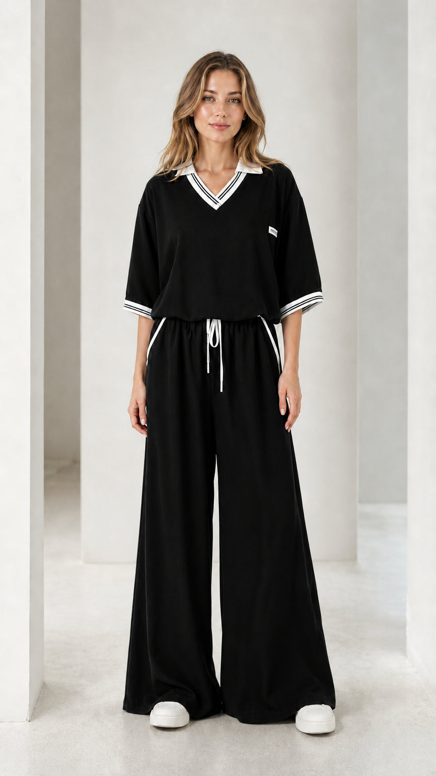 Front view of a black women's wide-leg jumpsuit with white striped trim