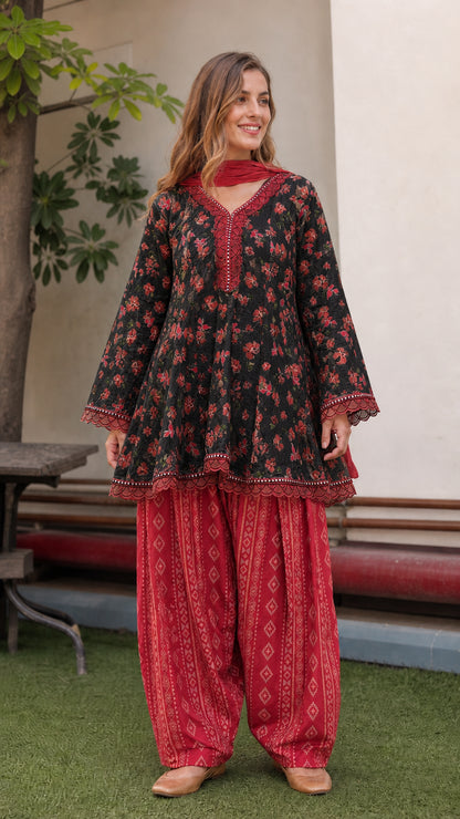 Model wearing black floral peplum tunic with red dhoti pants