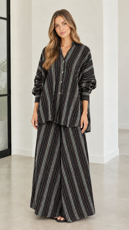 Model wearing black and white vertical striped oversized shirt and wide-leg trousers set