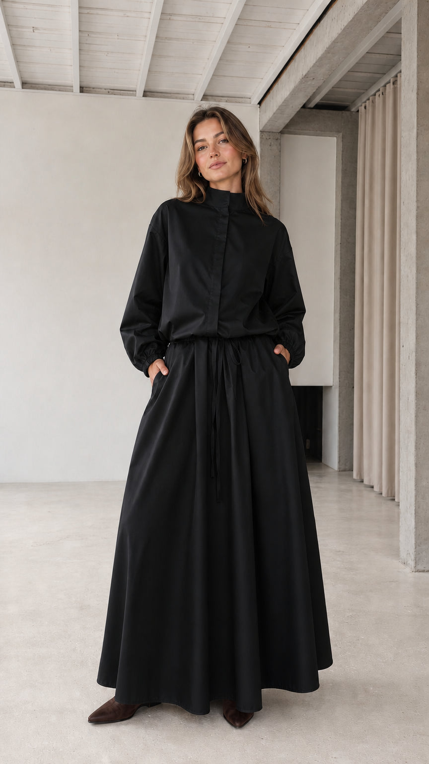 Front full view of woman wearing black stand collar drawstring maxi dress