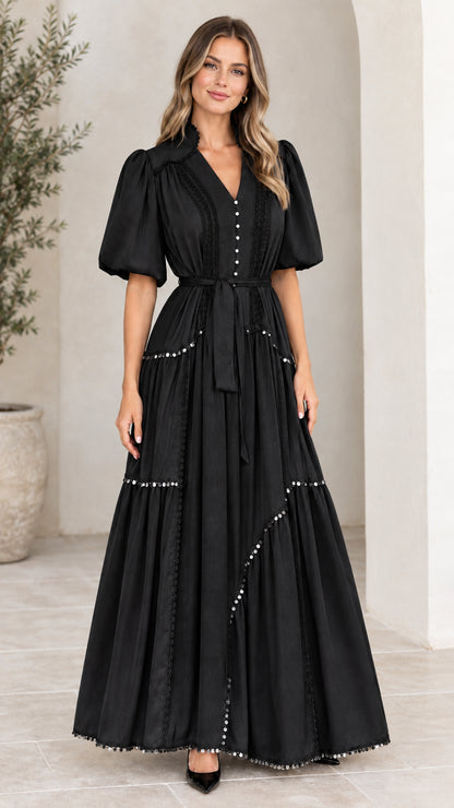 Front view of woman wearing black V-neck puff sleeve tiered maxi dress