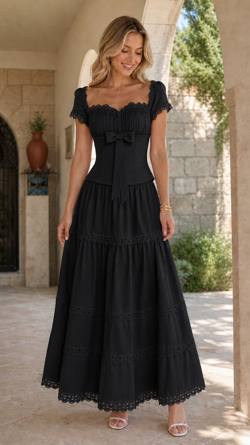 Model wearing black lace-trimmed tiered maxi dress with cap sleeves in front view