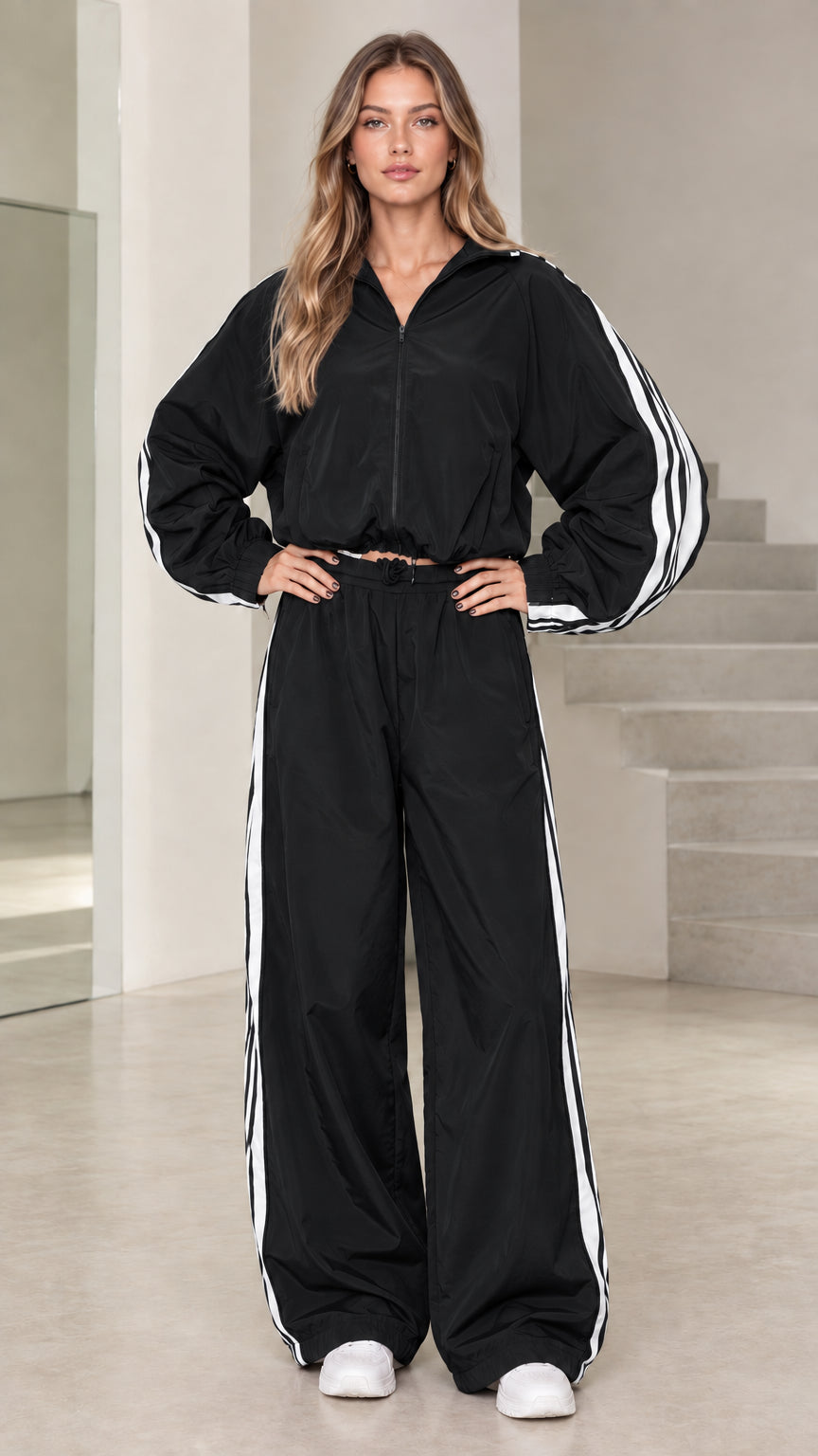 Front view of model wearing black hooded windbreaker tracksuit set with white side stripes