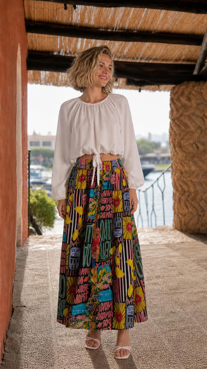 Model wearing white crop top and black multi printed maxi skirt