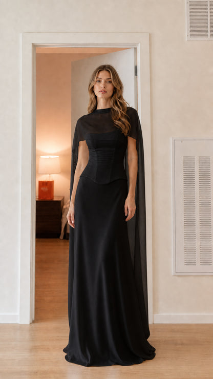 Front view of black mock neck corset evening maxi dress with attached cape