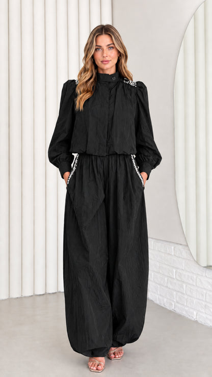 Front view of model wearing black rhinestone mock neck long sleeve jumpsuit