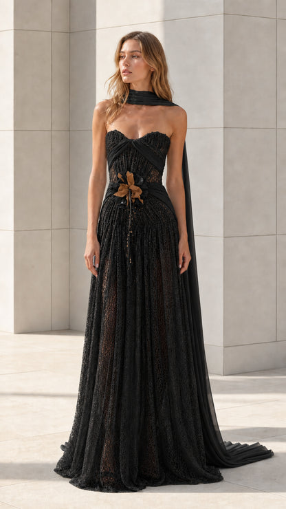 Front view of black strapless lace evening gown with draped scarf
