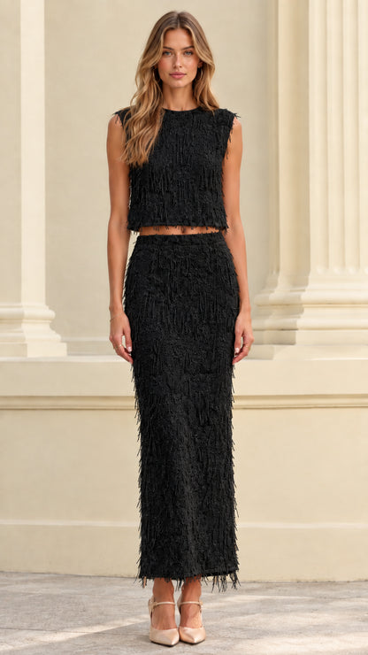 Front full view of woman wearing black textured fringe crop top and maxi skirt set