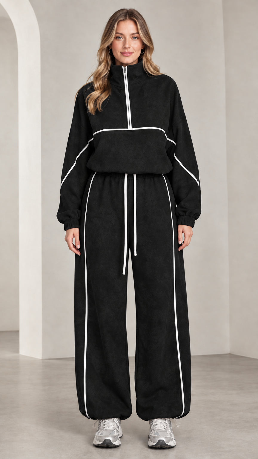 Front view of woman wearing black quarter-zip tracksuit set with white contrast piping