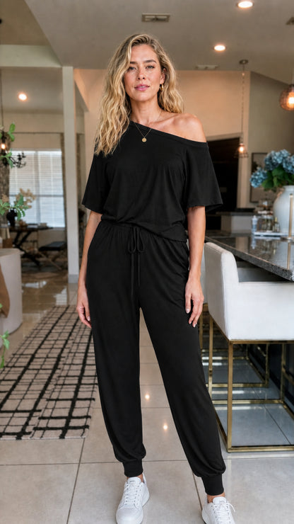 Front view of woman wearing black off-the-shoulder jumpsuit