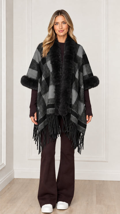 Woman wearing charcoal grey plaid poncho wrap with black faux fur trim