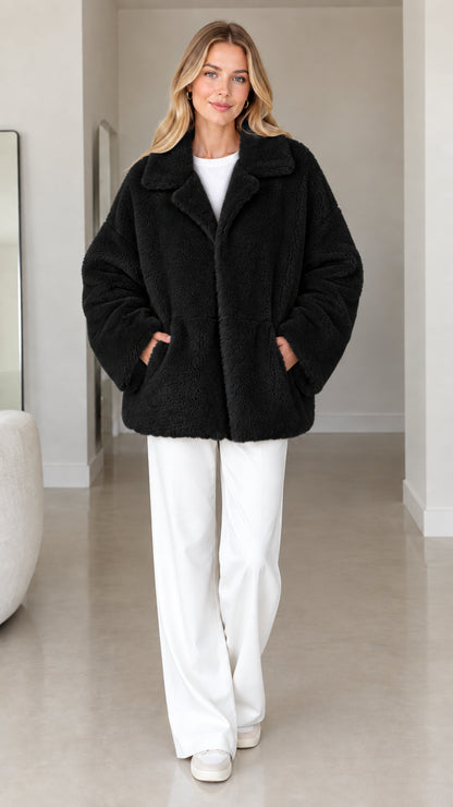 Front view of model wearing black plush faux fur lapel coat