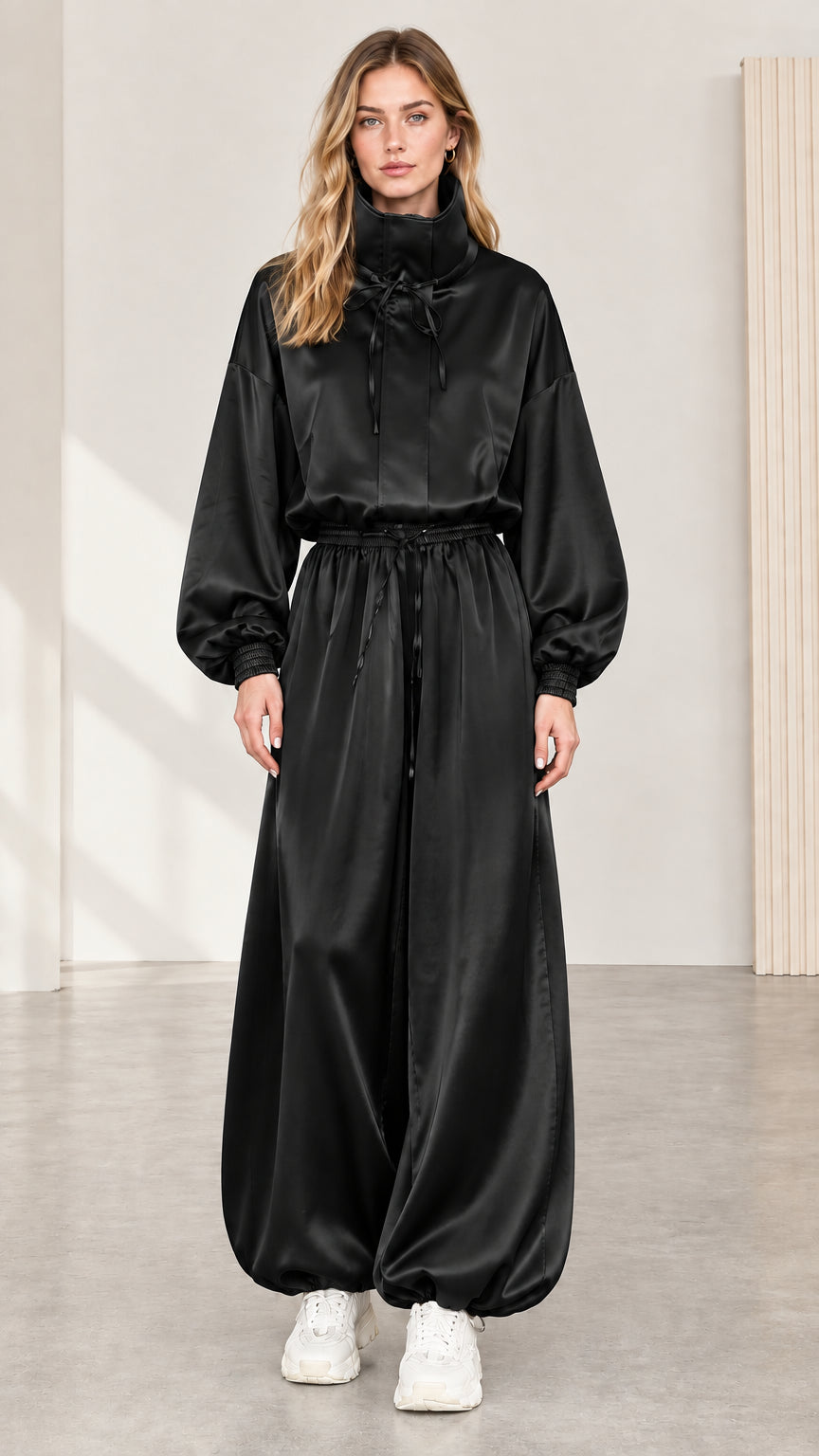 Full front view of model wearing black satin high neck balloon jumpsuit