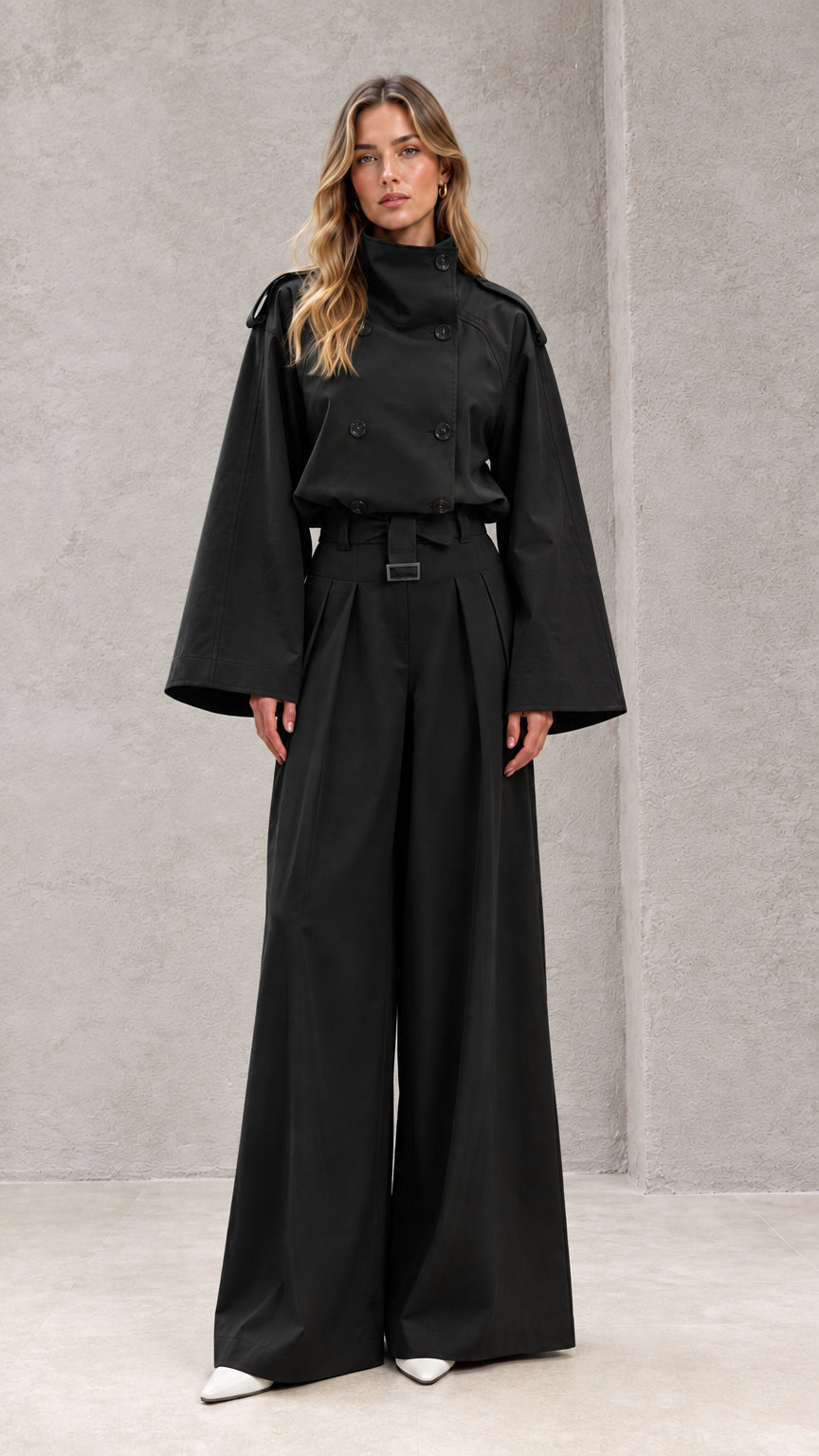 Front full-length view of model in black double-breasted wide-leg trench jumpsuit