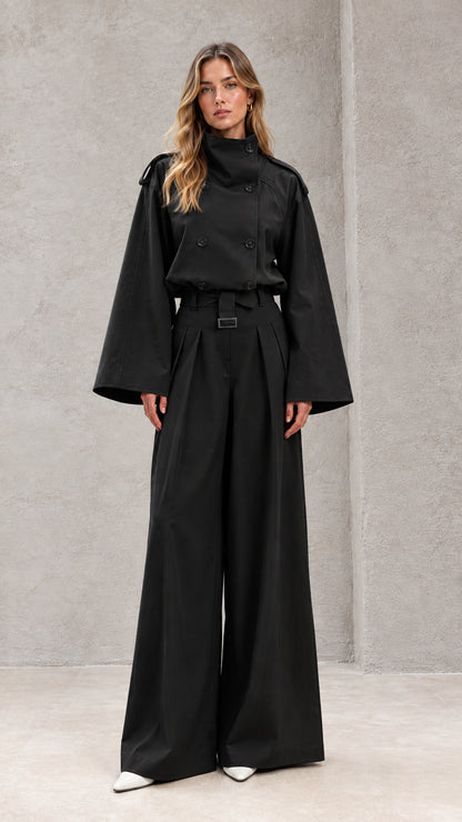 Front full-length view of model in black double-breasted wide-leg trench jumpsuit