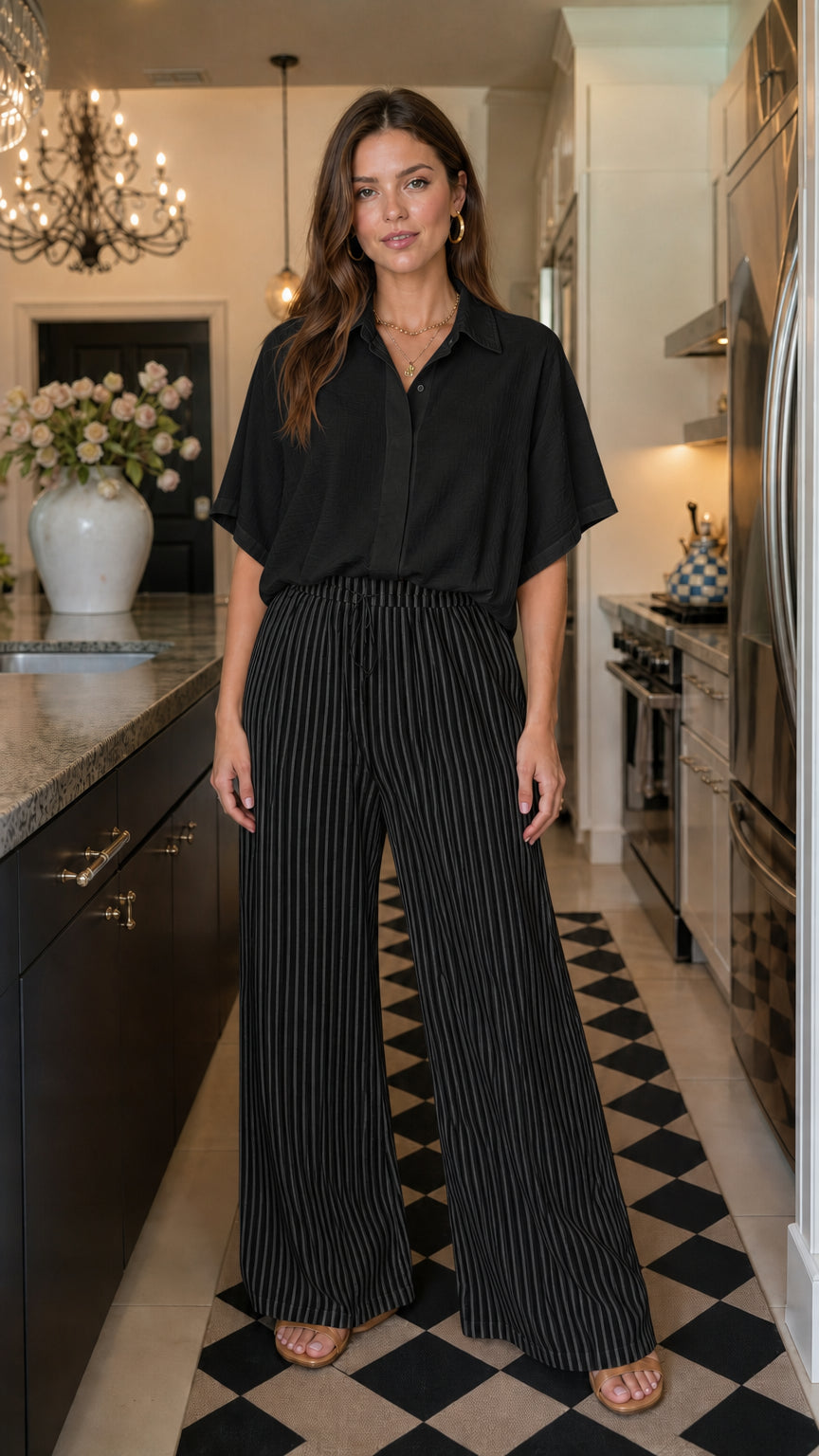 Woman wearing black matching button down shirt and striped wide leg pants