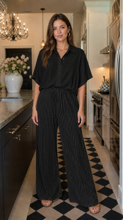 Woman wearing black matching button down shirt and striped wide leg pants