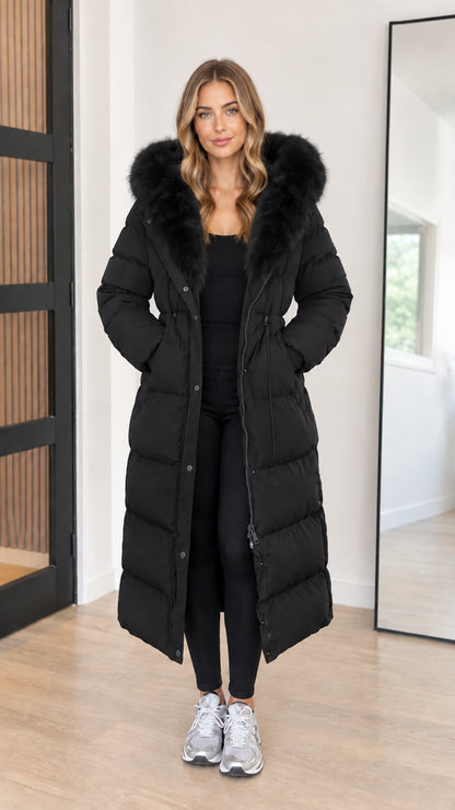 Full length view of women's black hooded maxi puffer coat with black faux fur trim