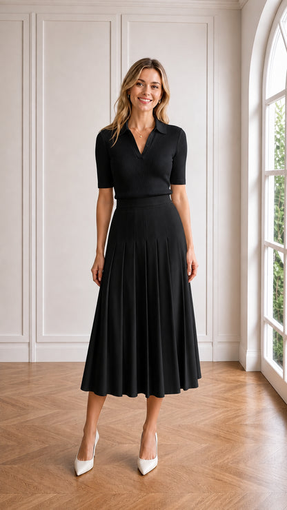 Model wearing black monochrome pleated midi skirt and knit polo outfit