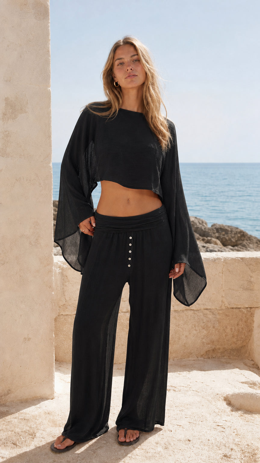 Woman wearing black two-piece bell sleeve crop top and wide leg pants