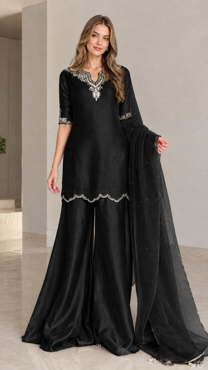 Model wearing black embellished kurta sharara 3-piece set with matching dupatta
