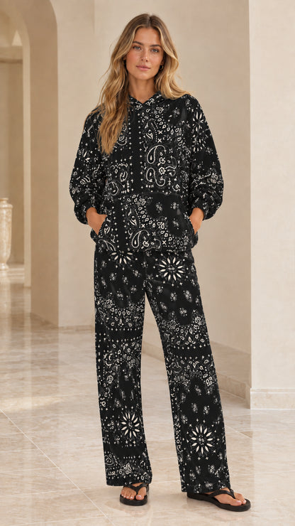 Full-body view of woman wearing black bandana print hoodie and wide-leg lounge pants set