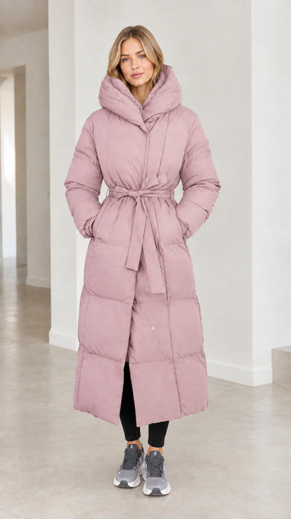 Front view of model wearing dusty pink long belted hooded puffer coat