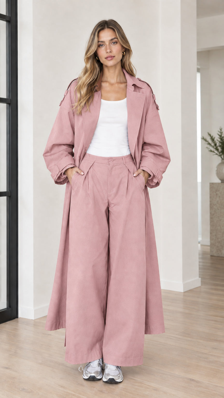 Woman wearing dusty pink long duster trench coat and matching wide-leg trousers set