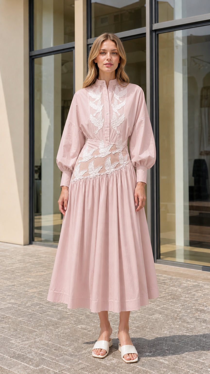 Model wearing blush pink embroidered pleated midi dress with stand collar