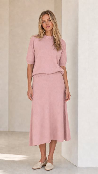 Woman wearing pink knit top and matching midi skirt set