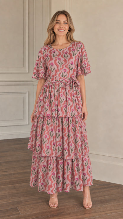 Front view of model wearing dusty pink floral wave print tiered maxi dress