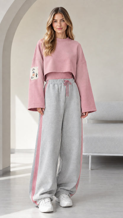 Model wearing pink cropped sweatshirt and grey wide leg sweatpants with pink side stripe